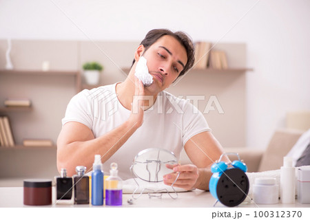 Young man shaving face at home Young man shaving face at home 100312370