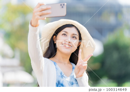 スマホで記念撮影する若い女性 100314649