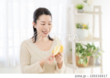 バナナを手に皮を剥くミドルエイジの女性 100316817