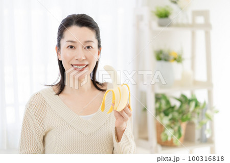 バナナを手に持つミドルエイジの女性 100316818