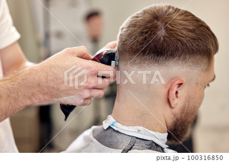 Barber trim hair with clipper on handsome bearded man Barber trim hair with clipper on handsome bearded man 100316850