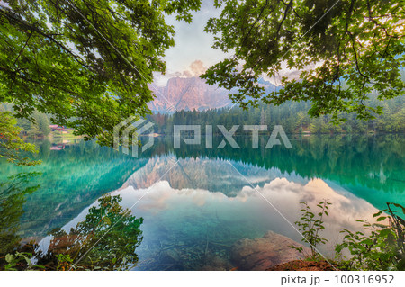 Incredible view of sunset over Fusine lake with Mangart peak on background. 100316952