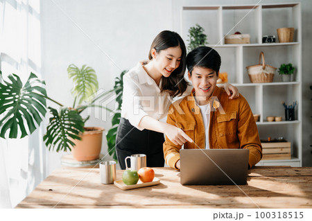 Two Asian business workers talking on the smartphone and using laptop at the home office. Two Asian business workers talking on the smartphone and using laptop at the home office. 100318515