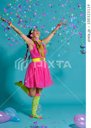 Lovely girl with a multi-colored braids hairstyle and bright make-up, posing in studio with air balloons and confetti against a blue background. Lovely girl with a multi-colored braids hairstyle and bright make-up, posing in studio with air balloons and confetti against a blue background. 100323114