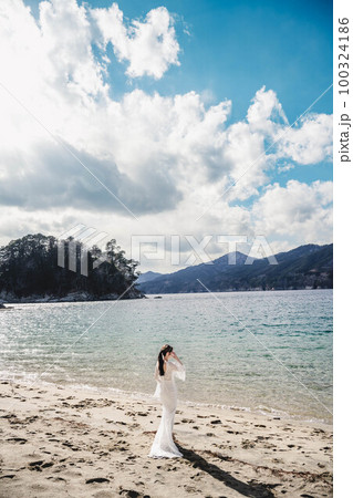 海辺でウエディングフォトを撮っている新婚夫婦 海辺でウエディングフォトを撮っている新婚夫婦 100324186