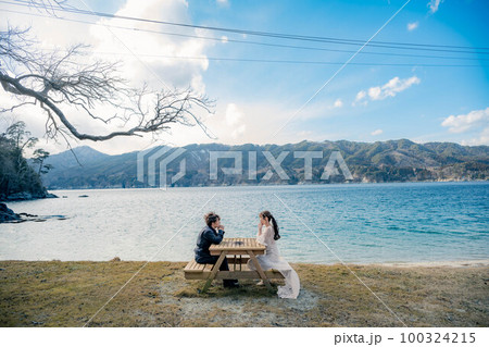 海辺でウエディングフォトを撮っている新婚夫婦 100324215