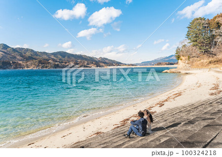 海辺でウエディングフォトを撮っている新婚夫婦 100324218