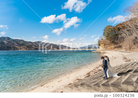 海辺でウエディングフォトを撮っている新婚夫婦 海辺でウエディングフォトを撮っている新婚夫婦 100324236