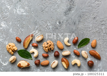 Composition of nuts , flat lay - mix hazelnuts, cashews, almonds on table background. healthy eating concepts and food background Composition of nuts , flat lay - mix hazelnuts, cashews, almonds on table background. healthy eating concepts and food background 100325311