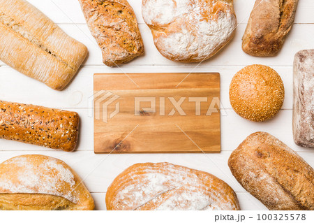Minimalist wooden cutting board blank mockup on background of Types of homemade bread. Different kinds of fresh bread as background, top view with space for your text or design Minimalist wooden cutting board blank mockup on background of Types of homemade bread. Different kinds of fresh bread as background, top view with space for your text or design 100325578