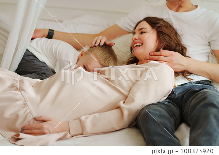 Happy pregnant mom, dad and son play in bed. the concept of family happiness. Happy pregnant mom, dad and son play in bed. the concept of family happiness. 100325920