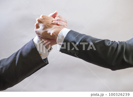 Two business partner to greet each other, branded handshake on gray background 100326239