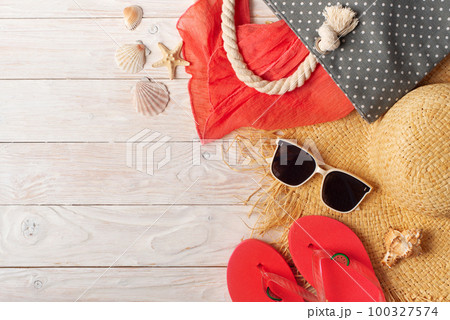 Straw hat sunglasses flip flops and beach bag with scarf on white wooden background Straw hat sunglasses flip flops and beach bag with scarf on white wooden background 100327574
