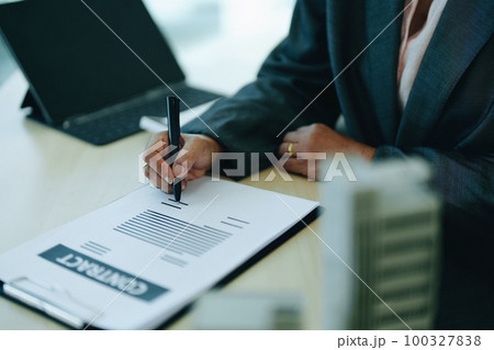 A businesswoman or a female business owner signs important documents to borrow money for investment in real estate or homes with the bank. 100327838