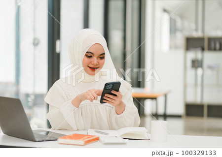 Muslim business lady wearing hijab and using smartphone in office. 100329133