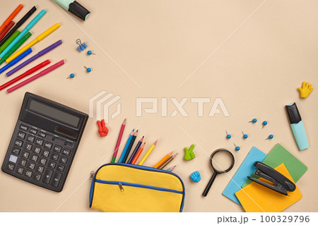 Flat lay photo of workspace desk with school accessories or office supplies on pink background. 100329796