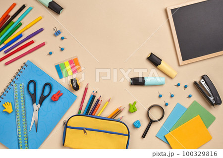 Flat lay photo of workspace desk with school accessories or office supplies on pink background. 100329816