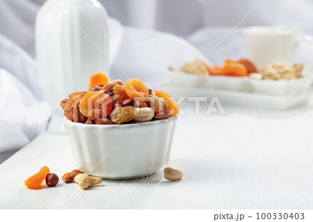 Dried fruits and assorted nuts on a white table. 100330403