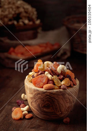 Dried fruits and assorted nuts on a wooden table. 100330404