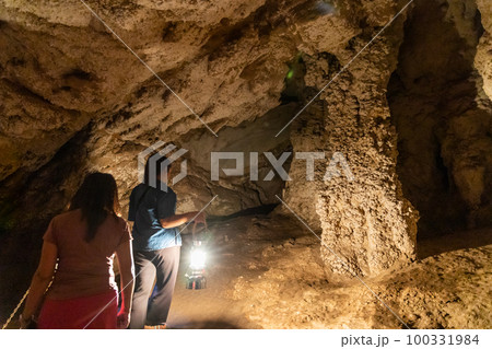 Local tour guide with traditional lantern guiding tourists through the dark chambers of Tham Nam Lod caves Local tour guide with traditional lantern guiding tourists through the dark chambers of Tham Nam Lod caves 100331984