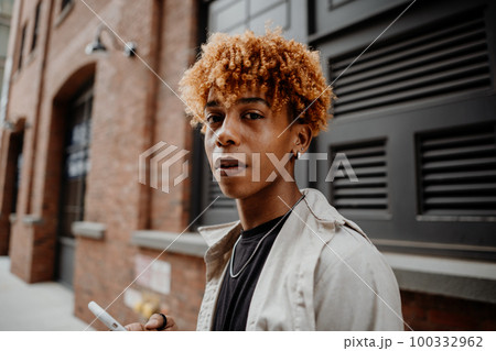 Portrait of the young african american man with serious expression leaning on the wall at street Portrait of the young african american man with serious expression leaning on the wall at street 100332962