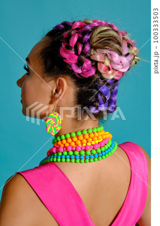 Lovely girl with a multi-colored braids hairstyle and bright make-up, posing in studio against a blue background. Lovely girl with a multi-colored braids hairstyle and bright make-up, posing in studio against a blue background. 100333503