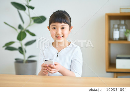 お家でスマホを操作する小学生の女の子 お家でスマホを操作する小学生の女の子 100334094