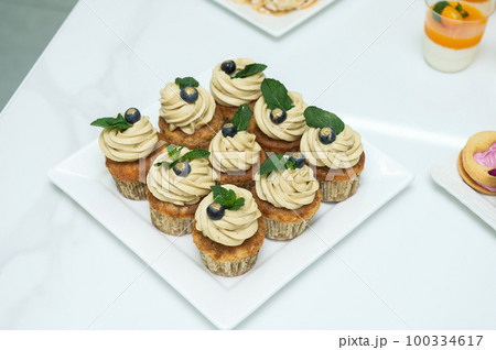 Cupcakes with cheese pistachio cream in a candy bar decorated with blueberries and mint 100334617