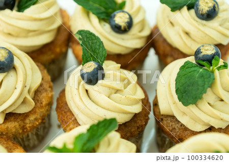 Cupcakes with cheese pistachio cream in a candy bar decorated with blueberries and mint in a plate 100334620