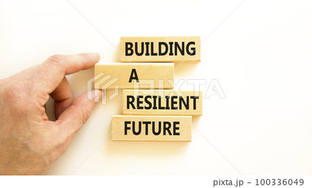 Building a resilient future symbol. Concept word Building a resilient future on wooden blocks. Beautiful white table white background. Business and building a resilient future concept. Copy space. 100336049