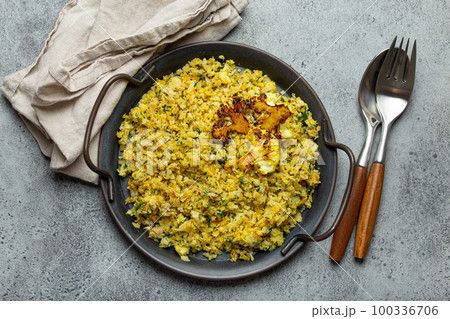 Fried cauliflower rice or couscous with dill on plate, healthy low carbohydrates vegetable side dish for keto diet and healthy low calories nutrition, rustic stone background 100336706