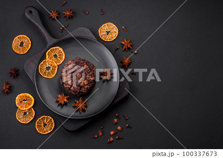Delicious fresh oatmeal round cookies with chocolate on a black ceramic plate 100337673