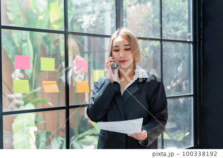 Portrait of a Happy business woman talking with a cell phone in hand holding documents Portrait of a Happy business woman talking with a cell phone in hand holding documents 100338192