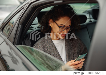 Pretty woman entrepreneur use phone during traveling to office in back seat of luxury car Pretty woman entrepreneur use phone during traveling to office in back seat of luxury car 100338230