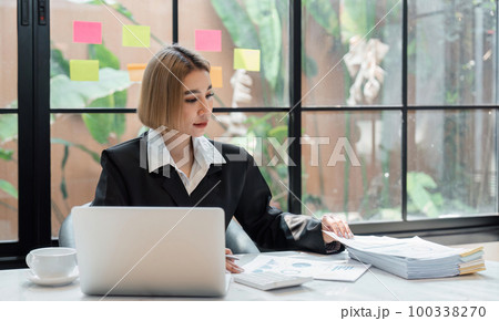 Attractive Asian businesswoman working on her laptop and documents in the office Attractive Asian businesswoman working on her laptop and documents in the office 100338270