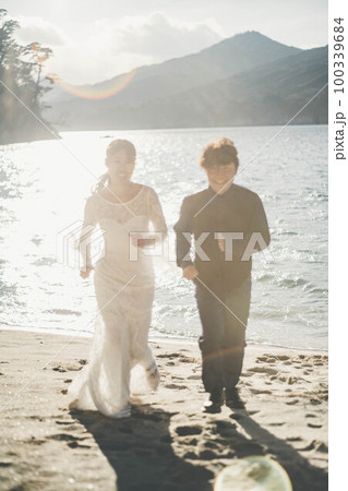 砂浜を走る新郎新婦 100339684