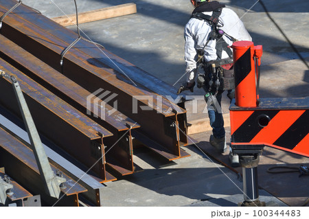 工事現場　トラックから鉄骨材の荷下ろし　とび職人の作業風景 100344483