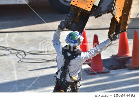 工事現場　トラックから鉄骨材の荷下ろし　とび職人の作業風景 100344492