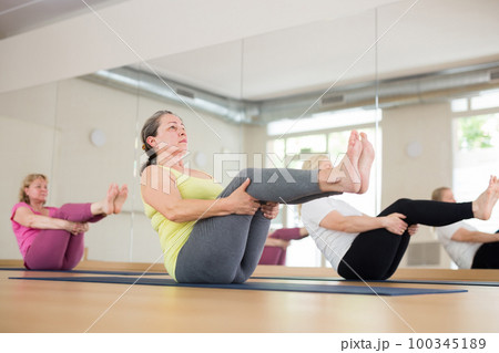 People relaxing and enjoying yoga elements - boat pose People relaxing and enjoying yoga elements - boat pose 100345189