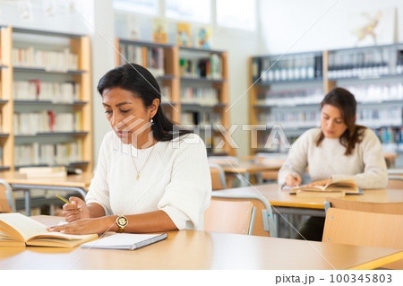Young adult woman studying in public library Young adult woman studying in public library 100345803