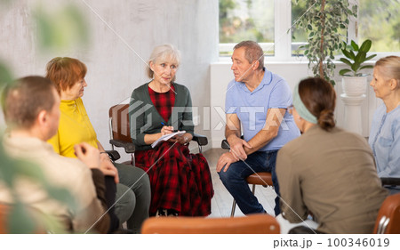 Aged woman conducting language speaking club for older adults Aged woman conducting language speaking club for older adults 100346019