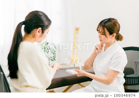 整骨院・接骨院で骨盤の病気の診察・相談・カウンセリングする整体師・マッサージ師の女性（困る・悩む） 100346974