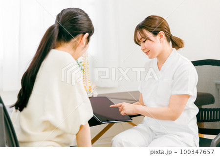 整骨院・接骨院でプランの説明・診察・相談・カウンセリングする整体師・マッサージ師・セラピストの女性 整骨院・接骨院でプランの説明・診察・相談・カウンセリングする整体師・マッサージ師・セラピストの女性 100347657