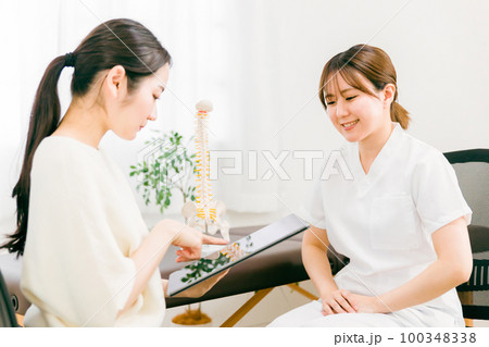 整骨院・接骨院で診察・相談・カウンセリングする整体師・マッサージ師・セラピストの女性(腰痛) 整骨院・接骨院で診察・相談・カウンセリングする整体師・マッサージ師・セラピストの女性(腰痛) 100348338