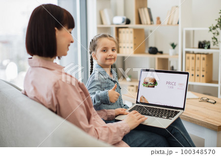 Woman and girl ordering fast food with discount on laptop Woman and girl ordering fast food with discount on laptop 100348570