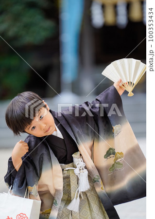 和服姿で七五三のお宮参りに来た5歳児が扇子片手におどけている図 和服姿で七五三のお宮参りに来た5歳児が扇子片手におどけている図 100353434