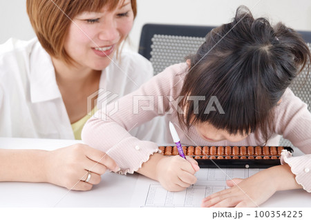 そろばん教室で生徒に講師が教えている様子 100354225