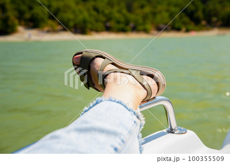 female leg in sandal, blue jeans on water pedal boat tourist catamaran on mountain lake on sunny day. summer leisure activities in public park. 100355509