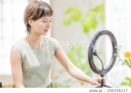 動画配信でフォロワーに話しかける若い女性 100356217