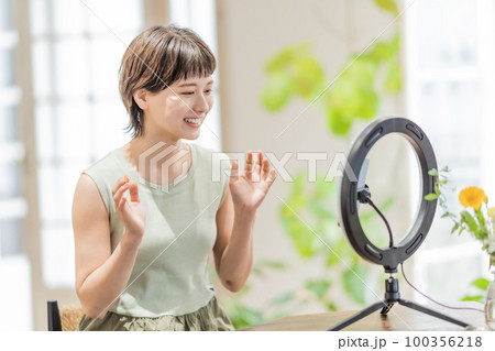 動画配信でフォロワーに話しかける若い女性 100356218